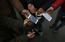 Un gruppo di migranti mostra i telefoni distrutti nel villaggio di Horgos, Serbia, nel gennaio 2020. Siamo vicino al confine ungherese