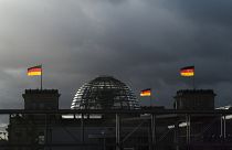 German national flags catch the sun on top of the German parliament building, the Reichstag building in Berlin, Germany, Friday, Nov. 29, 2019.