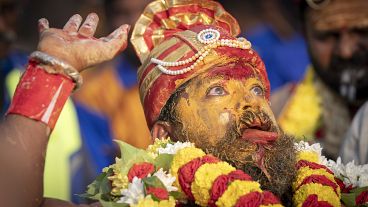 A Tamil Hindu priest has antiseptic powder on his face in a procession during the Thaipusam festival