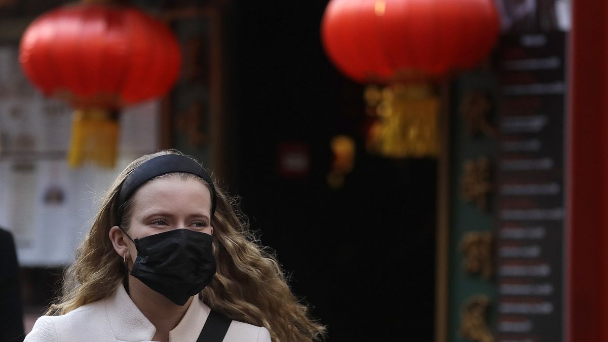 A woman wears a mask as she walks near China Town in London, Friday, Feb. 7, 2020. 