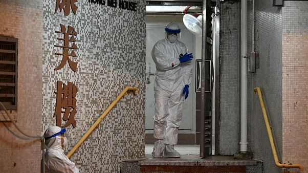 Medical personnels wearing protective suits wait near a block's entrance in the ground of a residential estate, in Hong Kong, on February 11, 2020 Medical personnels wearing protective suits wait near a block's entrance in the ground of a residential estate, in Hong Kong, on February 11, 2020
