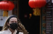 In Londons China Town trägt eine Frau eine Gesichtsmaske. 