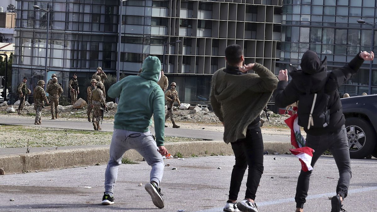 Anti-government protesters throw stones toward Lebanese army soldiers in downtown Beirut, Lebanon, Tuesday, Feb. 11, 2020.