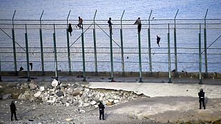 Migrants climb a fence that divides Morocco and Ceuta in this 2019 file photo