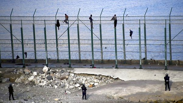 Migrants climb a fence that divides Morocco and Ceuta in this 2019 file photo Migrants climb a fence that divides Morocco and Ceuta in this 2019 file photo