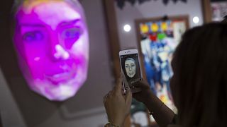 FILE PHOTO - A woman takes a photograph of her own portrait displayed in 3D at the NTT company stand during the Mobile World Congress wireless show, in Barcelona, Spain
