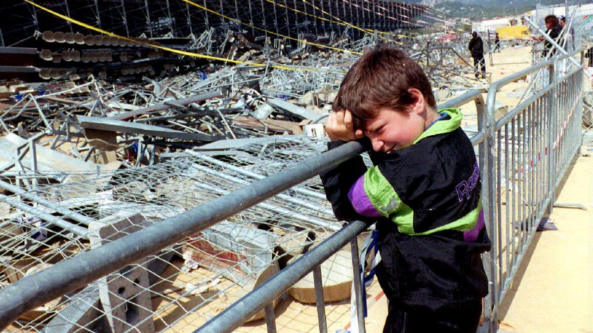 FILE PHOTO: A boy leans on a fence 06 May 1992 in front of the temporary stand at Furiani stadium in Corsica that collapsed 05 May.