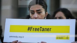 Human rights activists hold placards demanding the release of Amnesty's Turkey chairman Taner Kilic