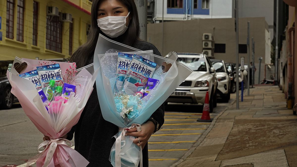 Flower shop owner Iris Leung wears her protective face mask as she delivers flowers with masks to customers on Valentine's Day in Hong Kong, Friday, Feb. 14, 2020.