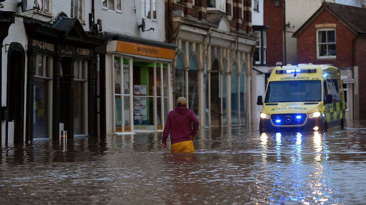 A man wades through flood water in Tenbury Wells, after the River Teme burst its banks in western England, on February 16, 2020.