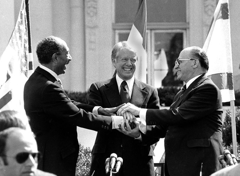 انور سادات، رئیس جمهور مصر (چپ)، جیمی کارتر، رئیس جمهوری ایالات متحده (وسط)، و مناخیم بگین نخست وزیر اسرائیل (راست) به تاریخ ۲۶ مارس ۱۹۷۹