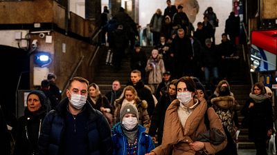 A family wearing a face mask walk in Biblioteka Imeni Lenina metro station in Moscow on February 7, 2020.