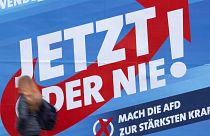 A woman walks in front of a campaign poster of the far-right Alternative for Germany (AFD) in Erfurt, Germany, Friday, Oct. 25, 2019