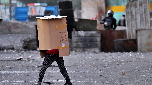 A protester covers his body while security force use slingshots to disperse anti-government protesters during clashes in downtown Baghdad, Iraq A protester covers his body while security force use slingshots to disperse anti-government protesters during clashes in downtown Baghdad, Iraq