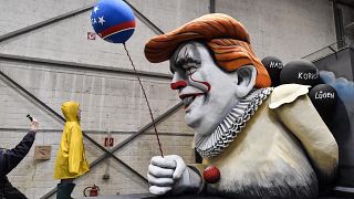 A man takes a picture of a satiric carnival float during a preview in a hall in Cologne, Germany. 