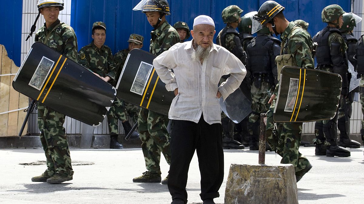 July 8, 2009, file photo, paramilitary police walk past an elderly ethnic minority man in Urumqi, western China's Xinjiang region. 