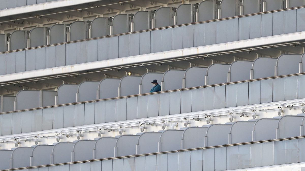 A passenger stands on the balcony of the quarantined Diamond Princess cruise ship at a port in Yokohama, near Tokyo, Friday, Feb. 21, 2020  
