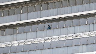 A passenger stands on the balcony of the quarantined Diamond Princess cruise ship at a port in Yokohama, near Tokyo, Friday, Feb. 21, 2020