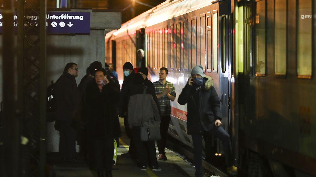 People stand on the platform near a train stoped by authorities at the train station on the Italian side of the Brenner Pass, Italy, Sunday, Feb. 23, 2020.