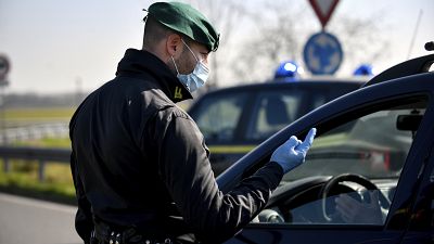 Un policier portant un masque s'entretient avec un conducteur d'un barrage routier à Casalpusterlengo, nord de l'Italie, le lundi 24 février 2020