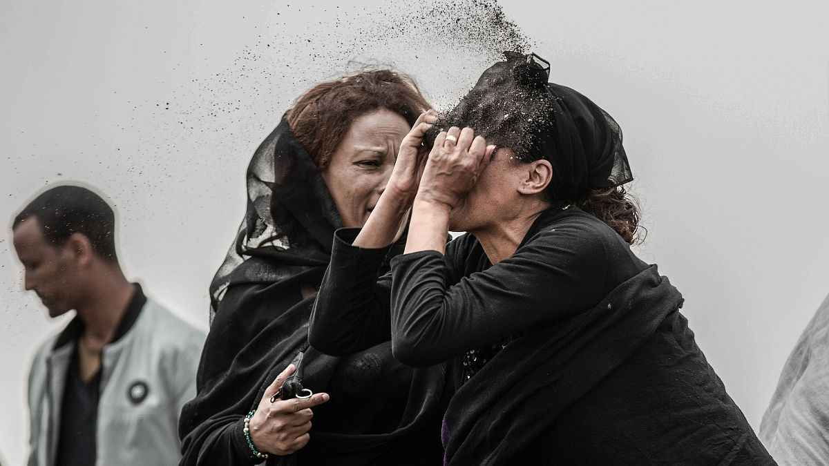 An Ethiopian relative of a crash victim throws dirt in her own face after realising that there is nothing physical left of her loved one.
