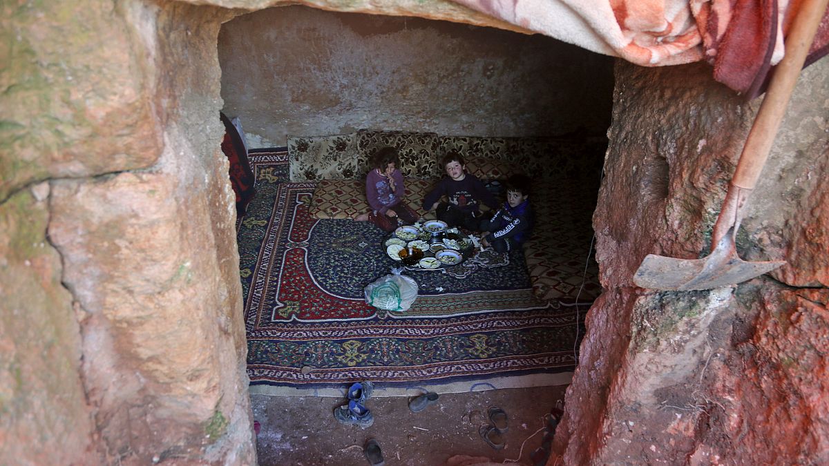 Members of a family of internally displaced Syrians eat together in an underground shelter where several families from Aleppo and Idlib provinces are taking refuge.