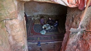 Members of a family of internally displaced Syrians eat together in an underground shelter where several families from Aleppo and Idlib provinces are taking refuge.