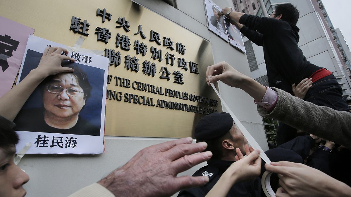 Protesters try to stick photos of missing booksellers, including Gui Minhai (L), outside the Liaison of the Central People's Government in Hong Kong, Jan. 3, 2016. 