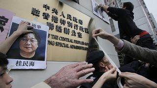 Protesters try to stick photos of missing booksellers, including Gui Minhai (L), outside the Liaison of the Central People's Government in Hong Kong, Jan. 3, 2016.