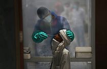 A health worker takes a nasal swab of a person for a COVID-19 test at a hospital in New Delhi, India
