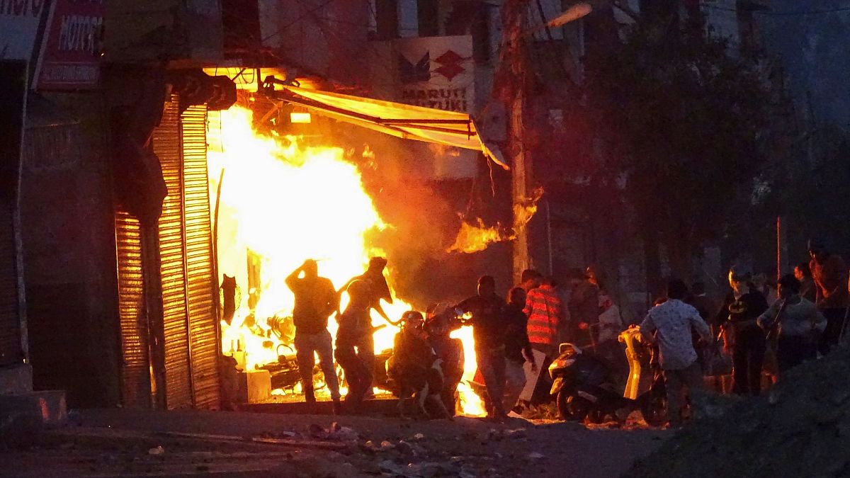 A shop burns as a mob sets it on fire during violent riots in New Delhi, India
