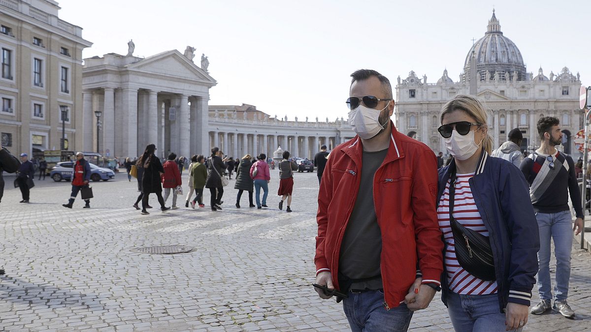 A couple wearing face masks, stroll outside St. Peter’s Square, at the Vatican, Thursday, Feb. 27, 2020.