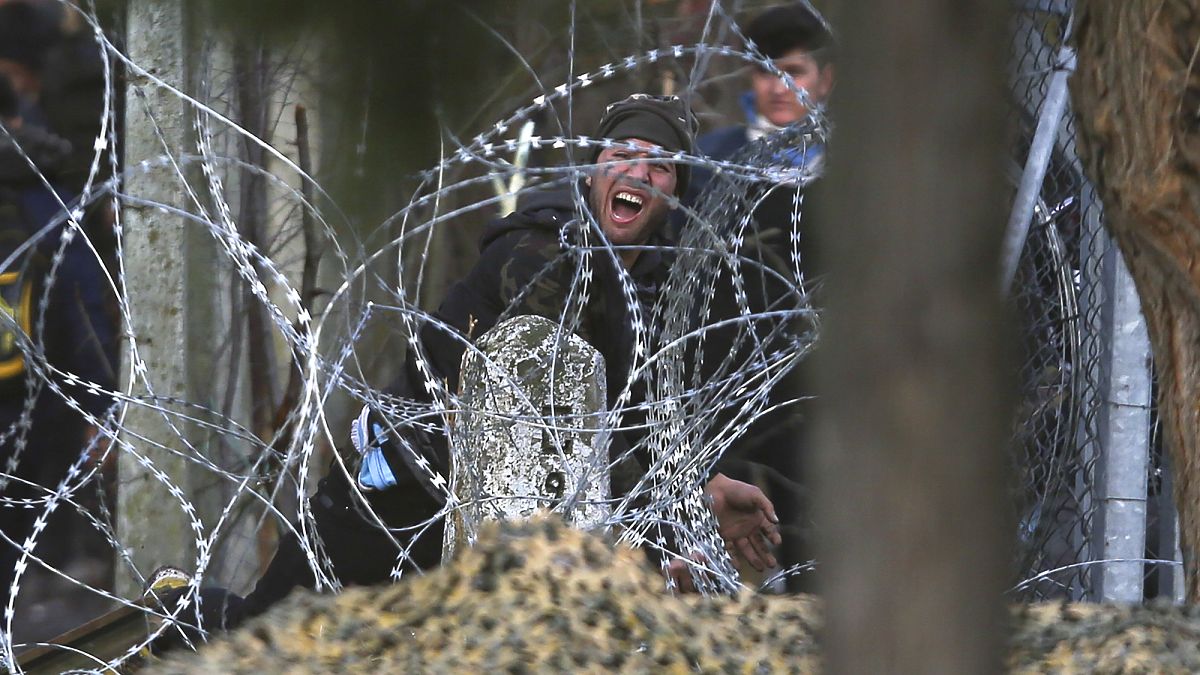 A migrant throws a stone at Greek police and army personnel during clashes near the Kastanies border gate at the Greek-Turkish border, Sunday, March 1, 2020.