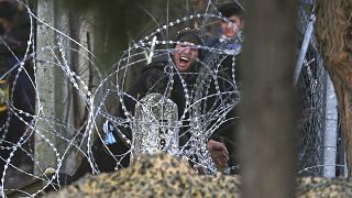 A migrant throws a stone at Greek police and army personnel during clashes near the Kastanies border gate at the Greek-Turkish border, Sunday, March 1, 2020.