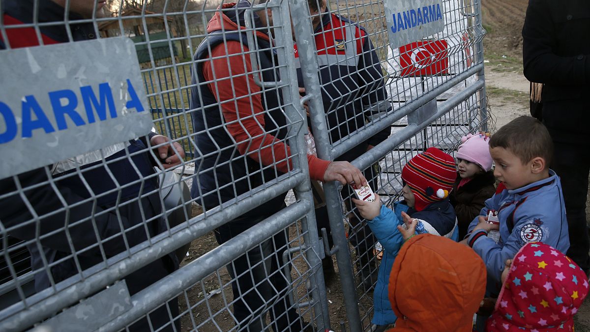 Um trabalhador de ONG distribui leite para crianças na fronteira entre a Turquia e a Grécia