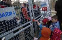 Um trabalhador de ONG distribui leite para crianças na fronteira entre a Turquia e a Grécia