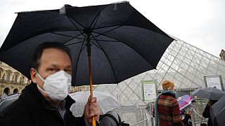 COVID-19 is placing huge demand on masks and gloves, the WHO warned. A tourist wears one outside the Louvre in Paris. 