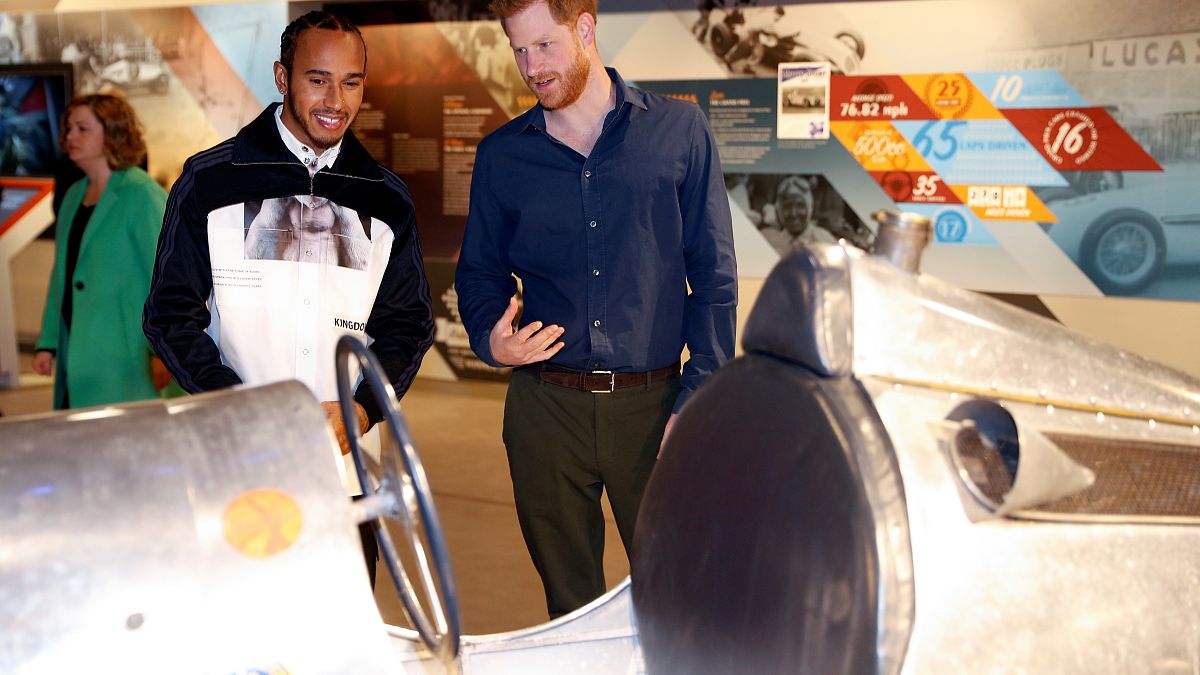 Rennfahrer Hamilton und Prinz Harry betrachten historischen Sportwagen
