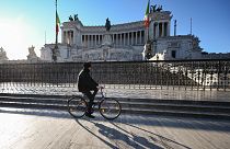 A man rides a bicycle past the Altare della Patria in Rome
