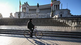A man rides a bicycle past the Altare della Patria in Rome