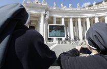 Nuns watch Pope Francis on a giant screen as he delivers the Angelus, in St. Peter's Square, at the Vatican, Sunday, March 8, 2020.