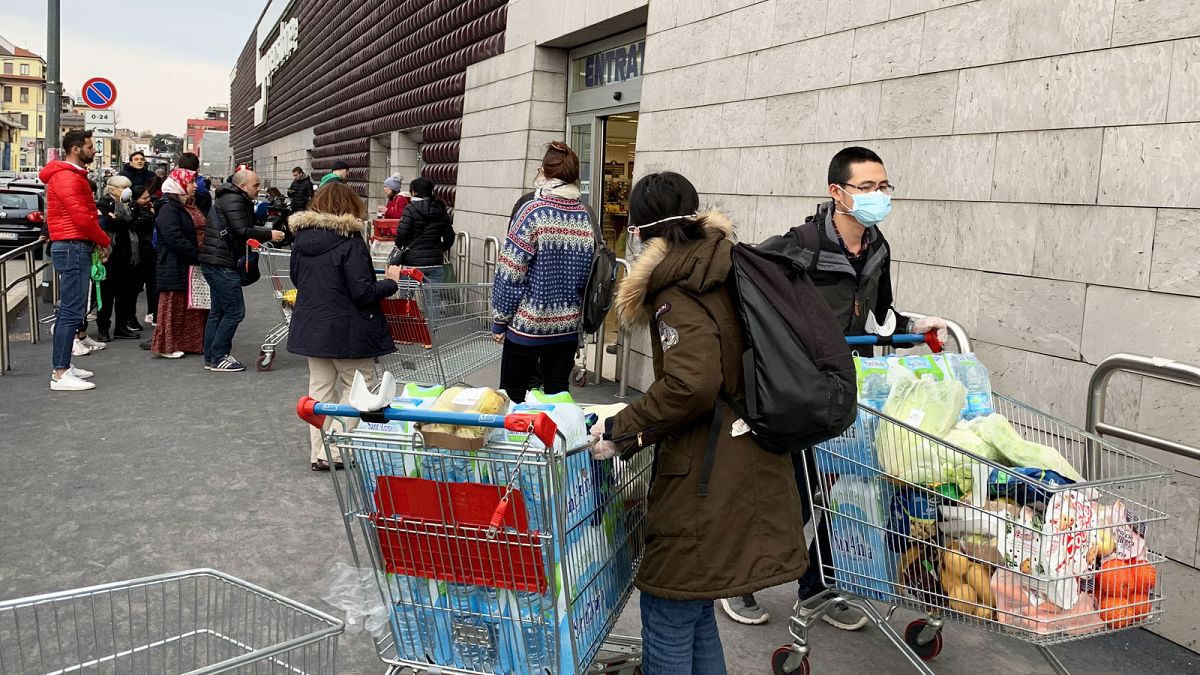 Des habitants de Milan, en Italie, portant des masques devant un supermarché, le 8 mars 2020. 