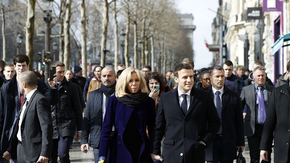 French President Emmanuel Macron and his wife Brigitte Macron walk down the Champs-Elysees avenue in Paris, Monday, March 9, 2020.