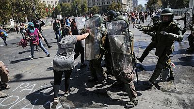 A woman struggles with riot police during clashes