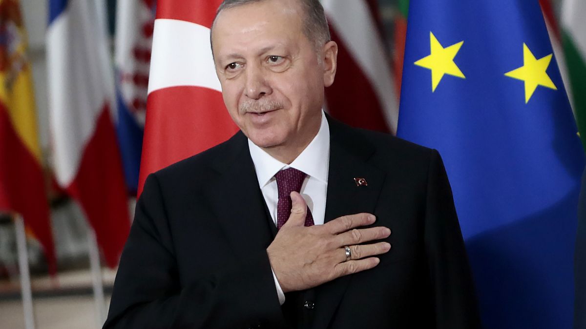 Turkish President Recep Tayyip Erdogan puts his hand over his heart in a gesture of hello prior to a meeting with European Council President Charles Michel.