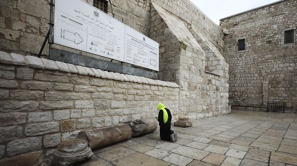 حاج مسيحي يصلي أمام كنيسة المهد في بيت لحم في الضفة الغربية المحتلة، حيث قررت السلطة الفلسطينية غلق الكنيسة بسبب انتشار فيروس كورونا حاج مسيحي يصلي أمام كنيسة المهد في بيت لحم في الضفة الغربية المحتلة، حيث قررت السلطة الفلسطينية غلق الكنيسة بسبب انتشار فيروس كورونا