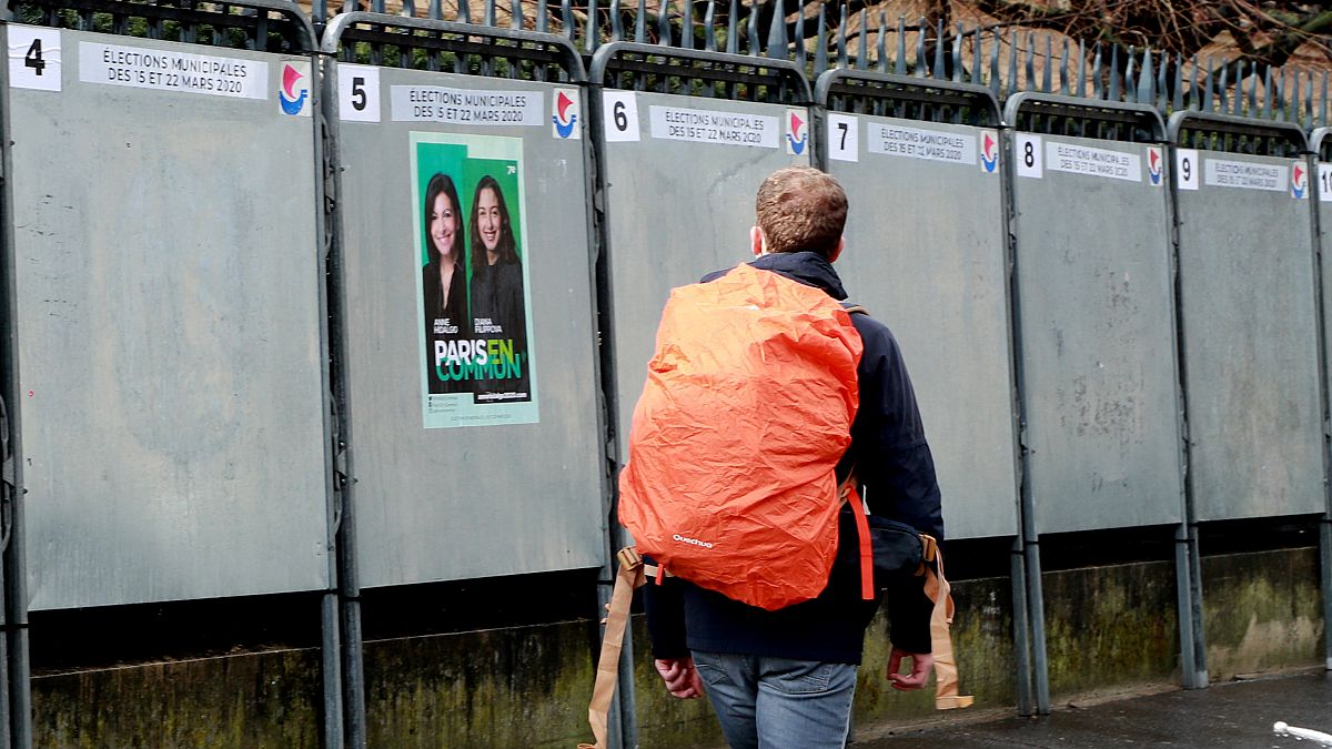 A man walks past a political poster depicting several of the candidats running in the upcoming French March 2020 mayoral elections.