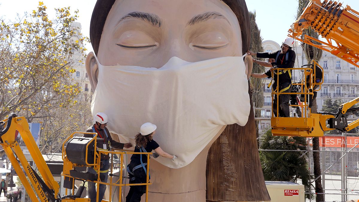 Munkások egy hatalmas maszkot helyeznek az egyik papírbábura a kelet-spanyolországi Valenciában 