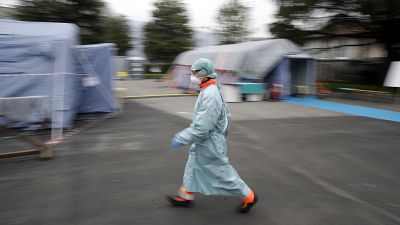 A staffer walks at one of the emergency structures that were set up to ease procedures at the Brescia hospital, northern Italy, Thursday, March 12, 2020. 