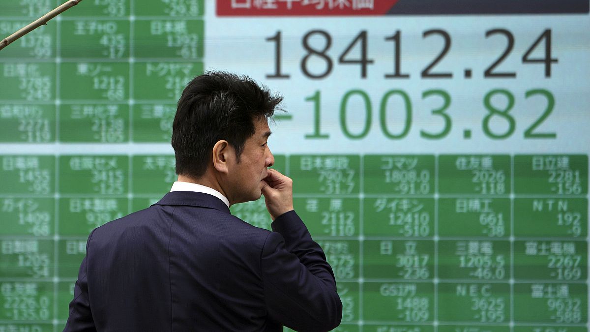 A man looks at an electronic stock board showing Japan's Nikkei 225 index at a securities firm in Tokyo Thursday, March 12, 2020. 